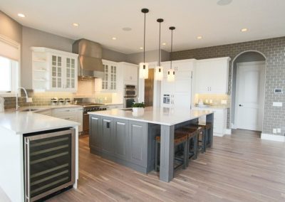 Kitchen Renovation showing island and white cupboards and lights hanging down