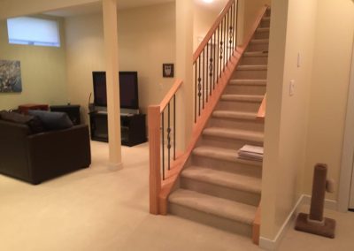 Basement showing couch and TV and game with great lighting, Staircase and carpet on floor.