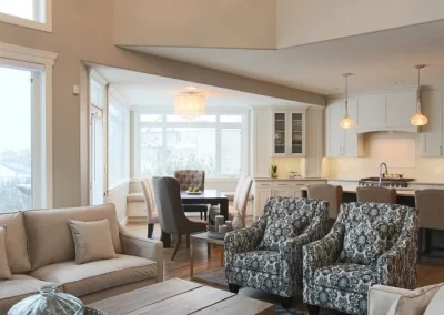 Living room with sofa and chairs and kitchen in background with table.